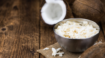 Old wooden table with fresh Coconut Chips (close-up shot; selective focus)