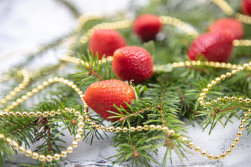 Obraz na płótnie Canvas A beautiful sprig of spruce decorated with strawberries. Fresh strawberries close-up, decoration for the Christmas tree.