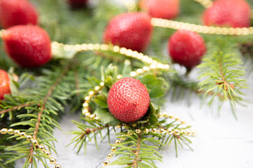 A beautiful sprig of spruce decorated with strawberries. Fresh strawberries close-up, decoration for the Christmas tree.