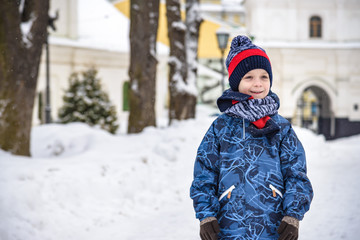 Fototapeta na wymiar Little boy walking in the park. Child going for a walk after school with a school bag in winter. Children activity outdoors in fresh air. Healthy way of life concept