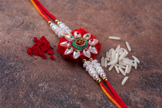 Raksha Bandhan : Rakhi with rice grains and kumkum on stone background, Traditional Indian wrist band which is a symbol of love between Brothers and Sisters.
