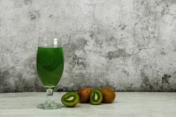 Green cocktail with kiwi in martini glasses with ice on a gray concrete background. Green cocktail...