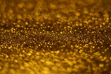 Golden glitter sandy background, gold sparkles blurry texture.