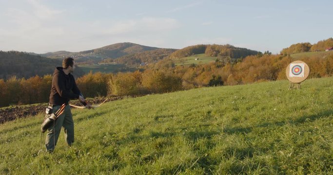 Archer shooting an arrow with a bow into target in countryside