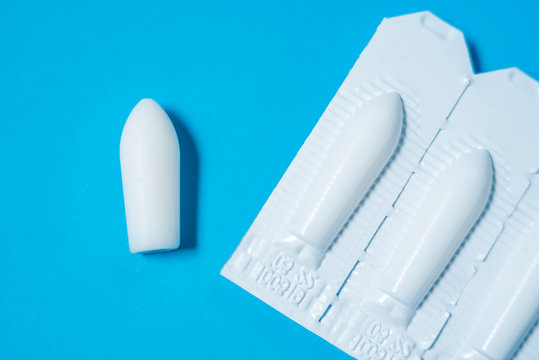 White suppositories for anal or vaginal use on blue background. Medical candles for treatment of Candida, thrush, hemorrhoids, inflammation and fever. Effective drug for timely treatment of diseases