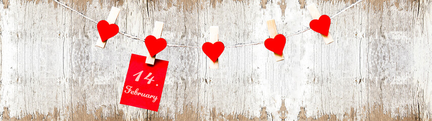 Happy Valentine's Day background banner panorama - Red paper note hang on wooden clothes pegs with wooden hearts on a string isolated on white rustic wooden wall with bokeh lights, with space for text