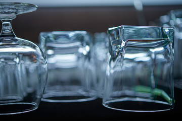 Clean washed and polished bar and pub glasses hanging over Close-up photo of rows of empty glasses on the showcase Empty clean bar glasses background