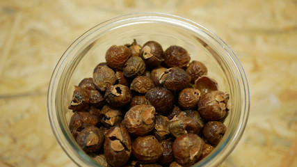 Soap nuts Indian soapberry or washnut glass jar cup, Sapindus mukorossi reetha or ritha from the soap tree shells are used to wash clothes to put drum washing machines. Nuts saponin plant fruit seeds
