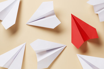 Flat lay of white paper airplanes and red paper airplane on background. Not like that. Individuality. Leader.
