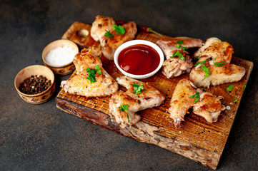 grilled chicken wings on a cutting board with spices and herbs on a stone background