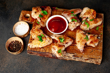 grilled chicken wings on a cutting board with spices and herbs on a stone background