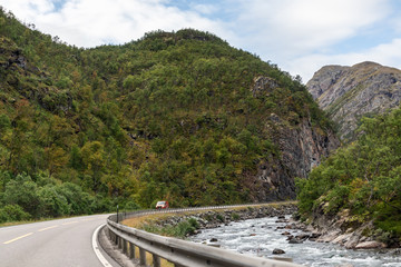 Mountains in Norway road near rocky river epic scenic sky, way, clouds view. Traveling by car, driving nature tourism. Dramatic skyscape northern scandinavian sky