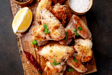 grilled chicken wings on a cutting board with spices and herbs on a stone background