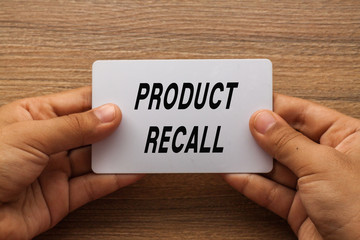 Product Recall written on white card holding with two hands - obrazy, fototapety, plakaty