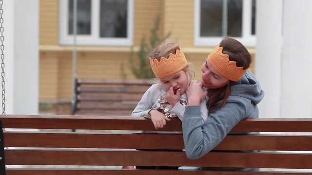Mom and daughter sit on a swing.