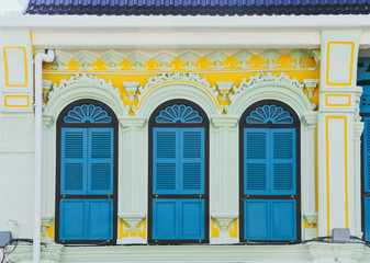 blue color wooden arched window on green and yellow cement wall in chino Portuguese style at Phuket old town, Thailand.