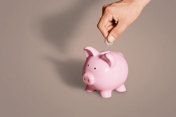 Businessman putting coin into the piggy bank