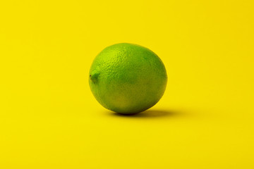 fresh green lime fruit on a yellow background