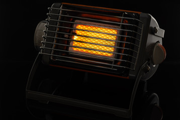 Camping portable gas ceramic heater, works and stands on a black glossy background