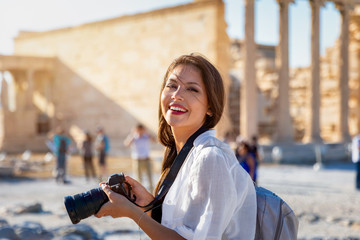 Portrait einer attraktiven Touristin mit Kamera in der Hand auf der Akropolis von Athen im Sommer, Griechenland - obrazy, fototapety, plakaty