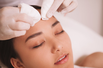 Cropped shot of a cosmetologist cleaning pores of a female client. Asian young woman having her...