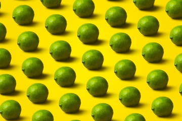 pattern with limes on yellow background. Minimal flat lay food texture