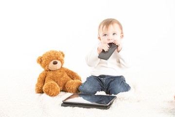 Stock studio photo with the white background of a baby's face with a mobile in his mouth next to a...