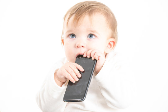 Studio photo with the white background of a baby's face with a mobile in his hands.