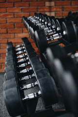 arrow a lot of dumbbells in the gym against the background of a brick wall