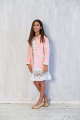 Fototapeta premium Portrait of a beautiful fashionable girl in a pink jacket and white dress