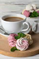 A cup of coffee with cream and delicious homemade marshmallows of different flavors and colors