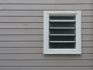 Close-up of white window on facade of horizontal sheets of painted wood. Tropical architecture. Martinique, French West Indies