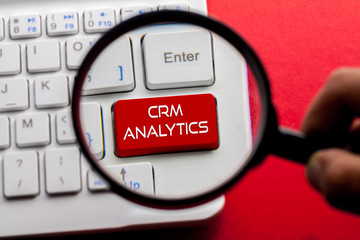 CRM ANALYTICS word written on keyboard view with magnifier glass