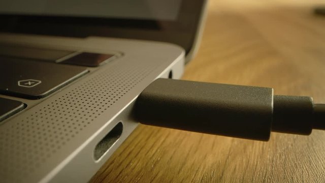 Close-up Macro Shot: Laptop on the Desk, Person Inserts USB-C Cable Adapter into Computer Port. 