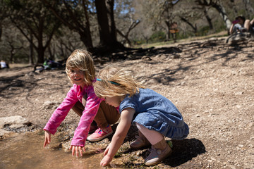 Young girls playing in natural stream under trees