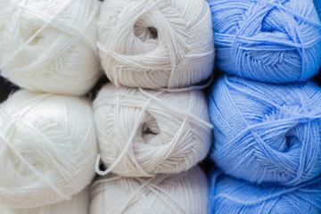 Multi-colored white blue and beige woolen threads in balls for knitting and handmade.