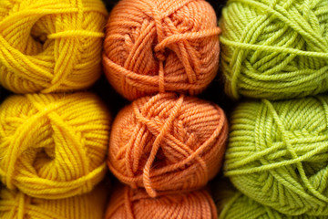 Multi-colored yellow, orange, lime green woolen threads in balls for knitting and handmade.