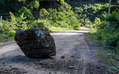 dramatic image of a large rock fallen on a rual road high in the caribbean mountains of the dominican republic.