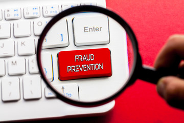 FRAUD PREVENTION word written on keyboard view with magnifier glass