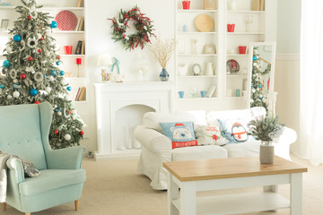The interior of the Christmas room, a white sofa with pillows at the coffee table and a blue chair.
