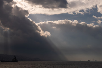 Lights falling into the city among the clouds. Dance of lights in Izmir Bay. Izmir skyline behind the lights