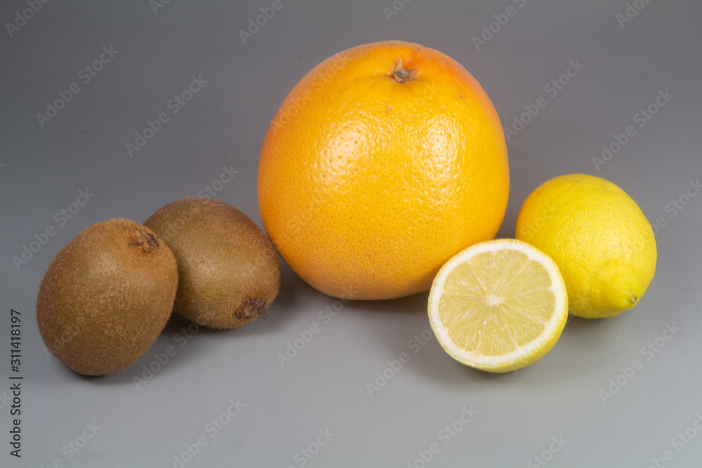 Wall mural grapefruit, kiwi and lemons on grey background