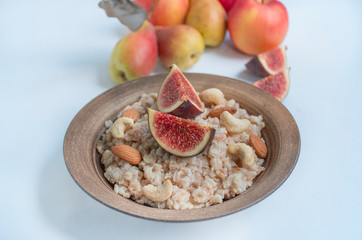 Oatmeal in a plate with fresh figs, almonds and cashews. Oatmeal with fruits. Healthy breakfast. Healthy food balance. Prepare food. White background.