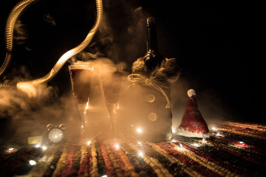 Red wine in crystal glass with bottle on colorful carpet with creative New Year artwork decorations. Copy space