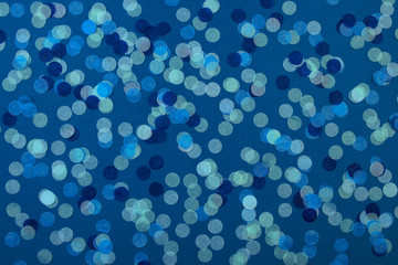 Festive multicolored confetti scattered on blue background. Holiday concept. Pastel polka dots texture.