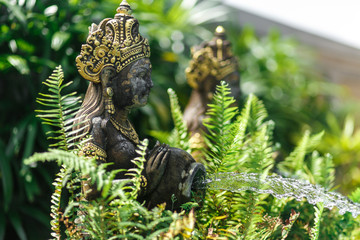 Balinese statuette of a girl with a pot from which water flows. Pool decoration