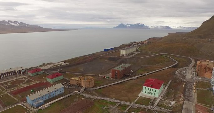 Drone aerial following the long technical pipe stretching by the ground along the coal mining settlement of Barentsburg, located on the coast of the Arctic Ocean in Spitsbergen. 4K