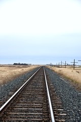 A railway track in the prairies leads to the horizon