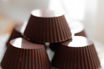 Chocolate curd cheese cake. Cake-shaped cottage cheese curds with a refined chocolate coating. Several chocolate brownies on a transparent plate.
