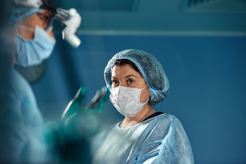 Two surgeons in protective uniform during the operation, on background of surgical room. Point of view shot